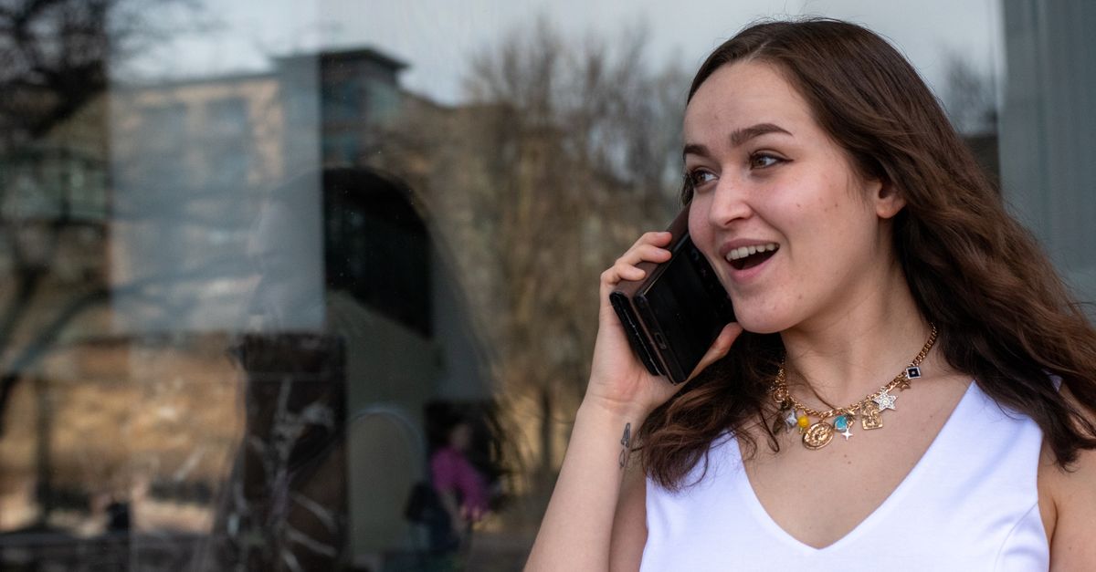 Smiling woman in white dress talking on smartphone, reflecting joy and connectivity.